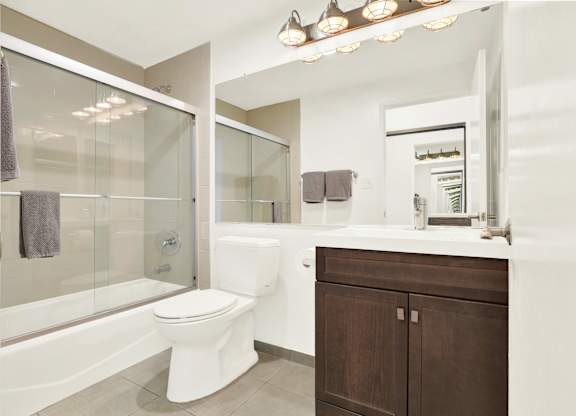 A white toilet sits in a modern bathroom with a glass shower at Twelve One Ten Rochester, Los Angeles