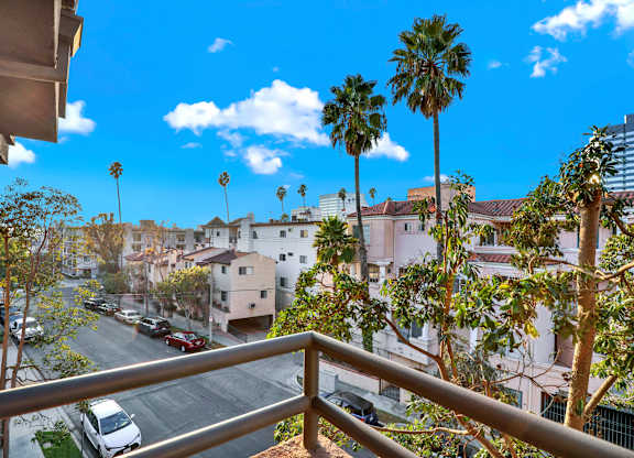 A balcony view of a residential area with palm trees at Twelve One Ten Rochester, Los Angeles