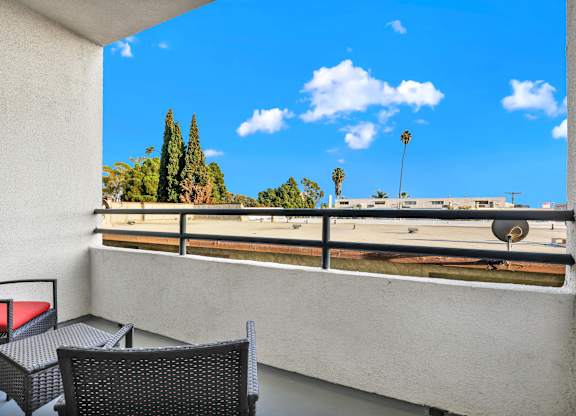 A balcony with a chair and table overlooking a parking lot at Twelve One Ten Rochester, Los Angeles, 90025