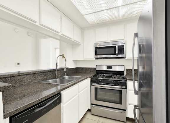A kitchen with a black countertop and stainless steel appliances at Peach Tree Court, Los Angeles, CA