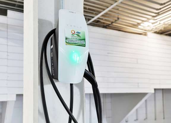 A Tesla charging station is plugged into a wall socket at Peach Tree Court, Los Angeles, California