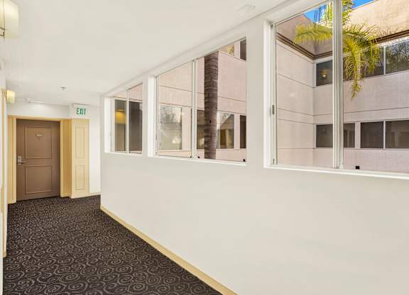 A hallway with a carpeted floor, white walls, and a door on the left at Peach Tree Court, California 90024