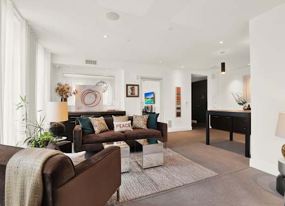 A living room with a brown couch and a white rug at The Urbanpolitan, Los Angeles, 90036