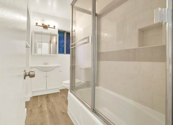 A white bathroom with a walk in shower at Wooster Encore Apartments, Los Angeles, CA