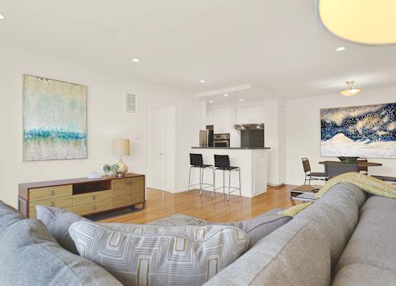 A living room with a grey couch and a painting on the wall at Wooster Encore Apartments, California 90035