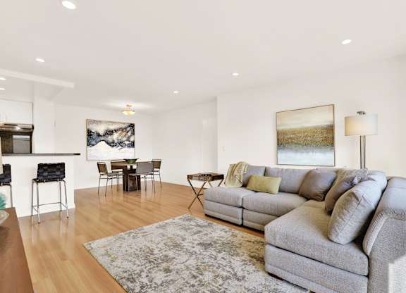 A living room with a grey couch and a rug at Wooster Encore Apartments, Los Angeles, CA 90035