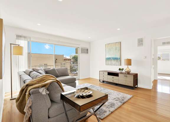A modern living room with a grey sofa and a coffee table at Wooster Encore Apartments, Los Angeles, California