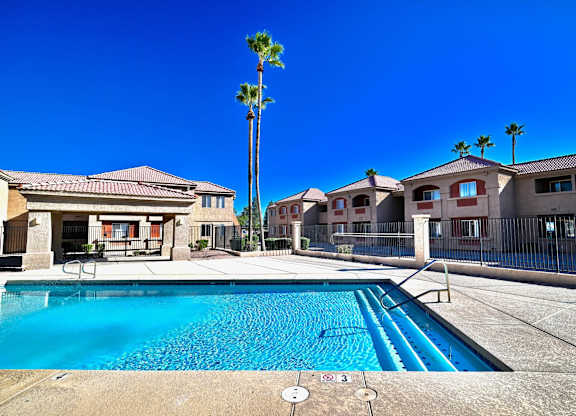 A pool in front of a house with a palm tree.