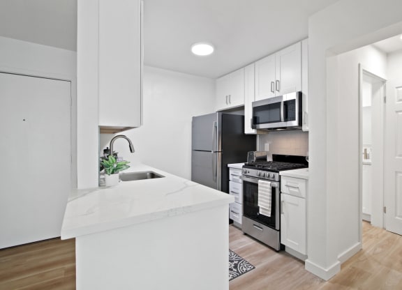 A kitchen with white cabinetry and stainless steel appliances at Harvard Manor, Irvine, 92612