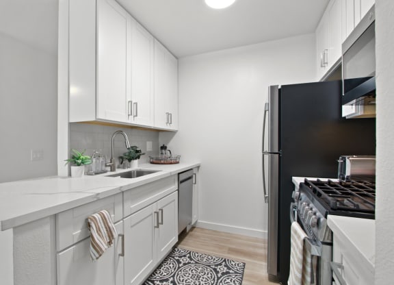 A kitchen with white cabinetry and black appliances at Harvard Manor, Irvine, CA