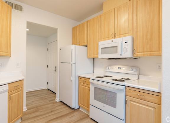 A kitchen with white appliances and wooden cabinets at Cornerstone at Gale Ranch Apartments, California