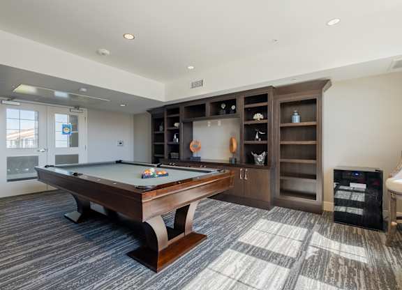 A room with a pool table and a cabinet with glass doors at Deer Creek Senior Apartments in San Ramon, CA 94582