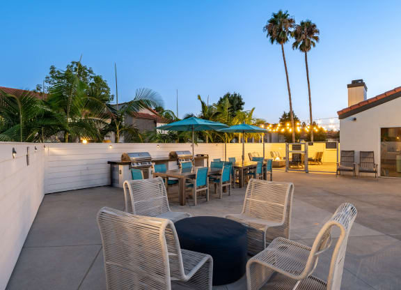 a rooftop patio with tables and chairs and palm trees at Laguna Gardens Apts., Laguna Niguel, California