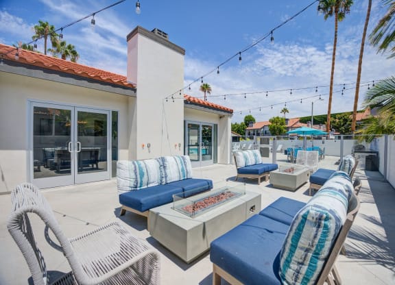 a patio with blue lounge chairs and a fire pit  at Laguna Gardens Apts., California