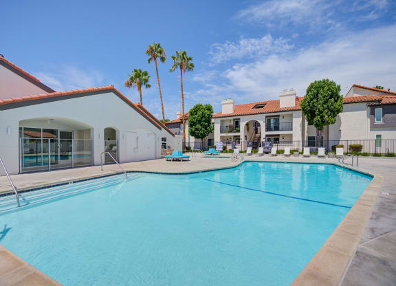 a large swimming pool with lounge chairs and palm trees in the background  at Laguna Gardens Apts., Laguna Niguel, California