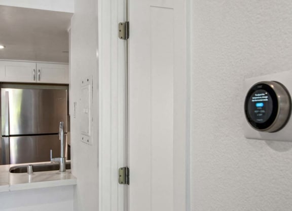 a white kitchen with a white door and a black thermostat on the wall  at Masselin Park West, Los Angeles, California