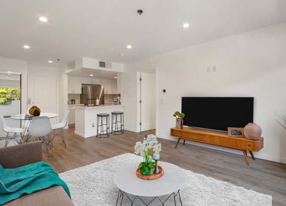 a living room with a television and a kitchen in the background  at Masselin Park West, California