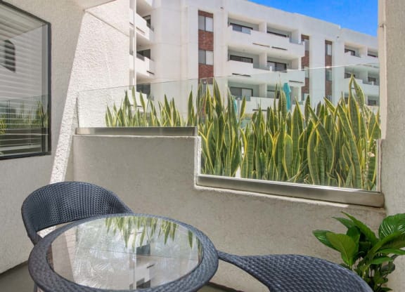 a table and chairs on a balcony with a building in the background  at Masselin Park West, Los Angeles, California