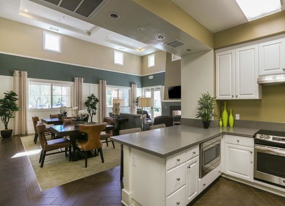 a kitchen with a stove top oven next to a table  at Ventana Senior Apartments, Northridge, CA