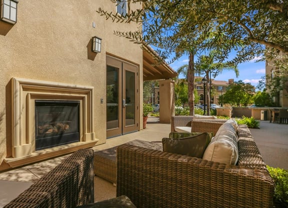 a patio with wicker furniture and a fireplace at Ventana Senior Apartments, Northridge, CA