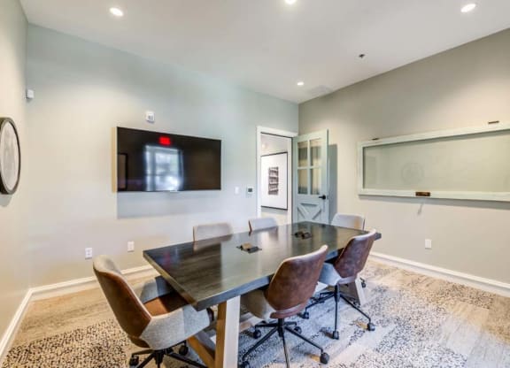 a conference room with a table and chairs and a tv on the wall  at The Vineyards Apartments, California