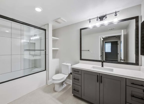 a bathroom with a toilet sink mirror and shower at The Vineyards Apartments, Porter Ranch, CA, 91326