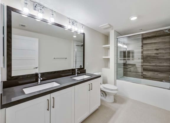 a bathroom with a toilet sink mirror and shower at The Vineyards Apartments, Porter Ranch, California