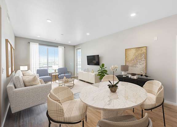 A living room with a white couch, a white coffee table, and a television.