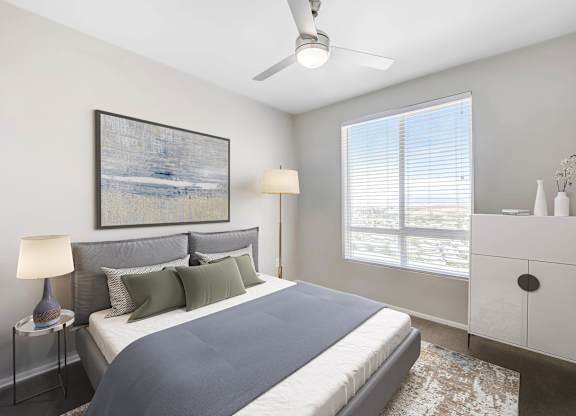 A bedroom with a bed, a nightstand with a lamp, a dresser, and a ceiling fan.