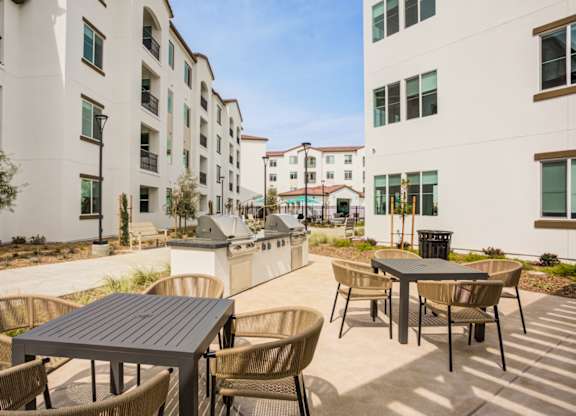 A patio with a table and chairs is surrounded by apartment buildings at Pradera Apartments, San Ramon, CA,  94582