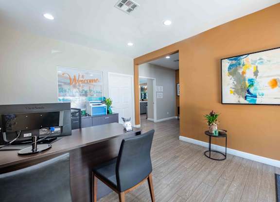 A room with a desk, chair, and a painting on the wall.