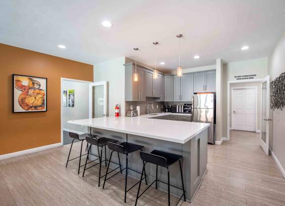 A kitchen with a white countertop and bar stools.