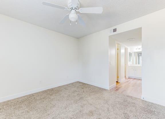 a bedroom with white walls and a ceiling fan  at Redlands Park Apts, Redlands, CA