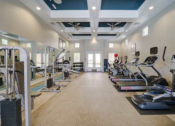 A spacious gym with a variety of equipment including treadmills, elliptical machines, and weight machines at Sonoma at Porter Ranch, CA, 91326