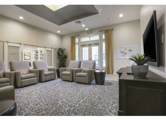 a room with couches and chairs and a tv on the wall  at Tesoro Senior Apartments, Porter Ranch