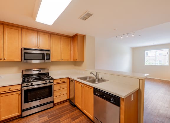a kitchen with wooden cabinets and stainless steel appliances  at Ventana Senior Apartments, Northridge, California