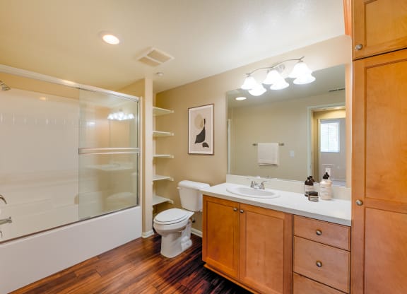 a bathroom with a toilet sink and shower  and mirror with vanity lights at Ventana Senior Apartments, Northridge, 91326