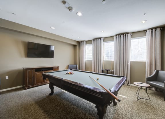 a game room with a pool table and a flat screen tv  at Ventana Senior Apartments, Northridge, 91326