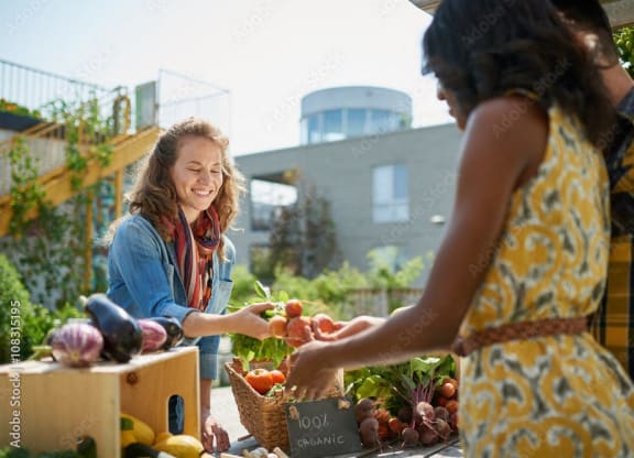 two women buying fruits and vegetables at an outdoor market at Darlington Apartments, Los Angeles, CA