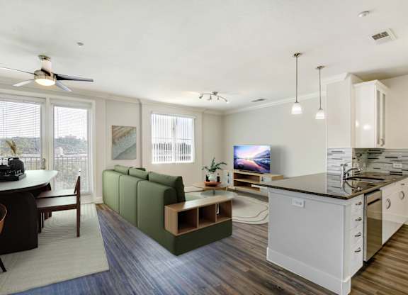 A modern kitchen with a green sofa and a dining table. at Apex Mission Valley, San Diego, CA, 92108