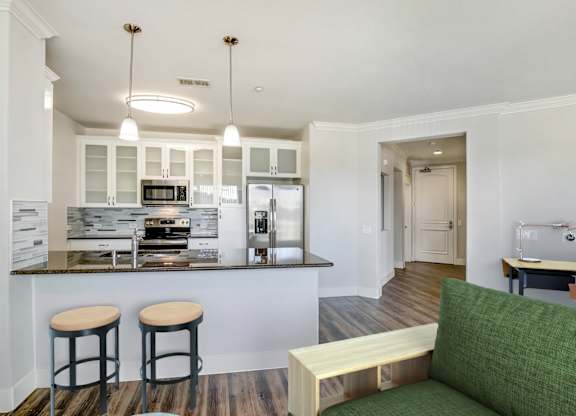 A kitchen with a bar area and a green couch. at Apex Mission Valley, San Diego