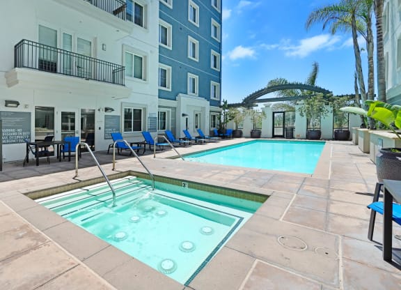 a swimming pool with blue chairs and a blue building in the background  at Apex Mission Valley, San Diego, California