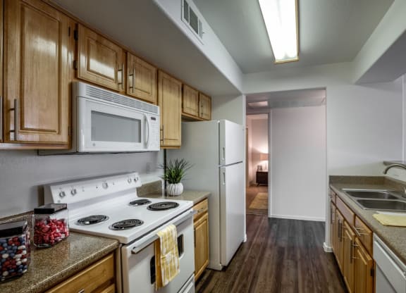 a kitchen with white appliances and wooden cabinets at Bella Terra Apartments, Henderson, NV
