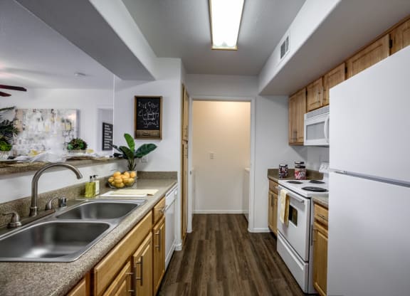 a kitchen with white appliances and wooden cabinets at Bella Terra Apartments, Henderson, 89012