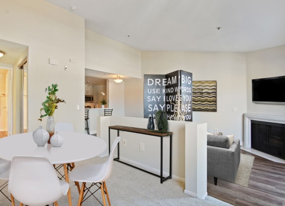 a dining area with a white table and chairs and a fireplace in the background at Palm Royale Apartments, California, 90034