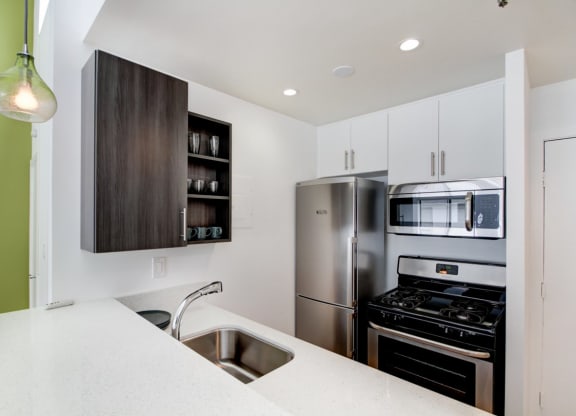 a kitchen with white cabinets and green walls  at El Greco Lofts, Los Angeles, 90024