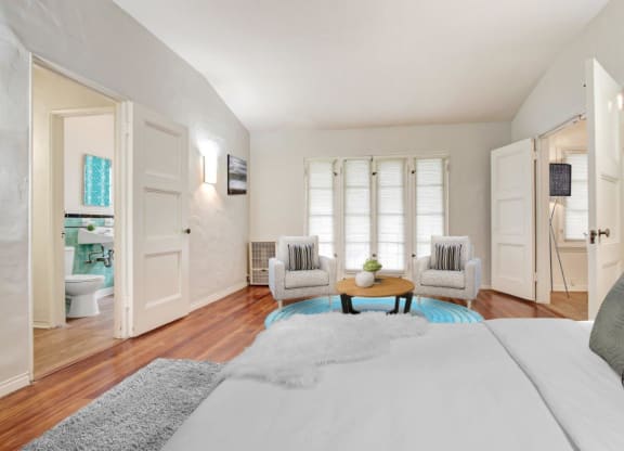 a bedroom with a large bed and two chairs in front of a window  at 1022 Tiverton, Los Angeles
