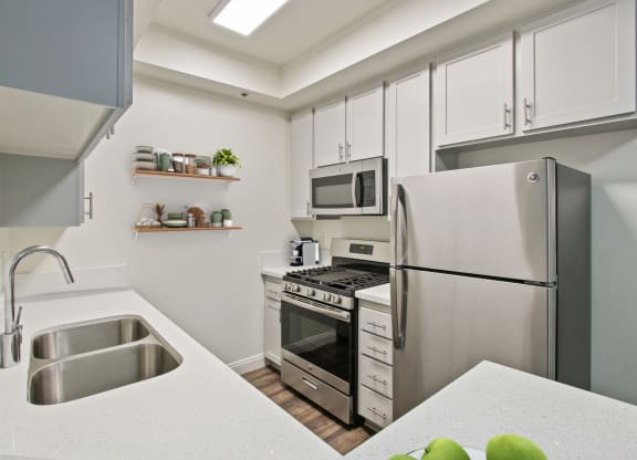 a kitchen with stainless steel appliances and a sink at Palm Royale Apartments, Los Angeles