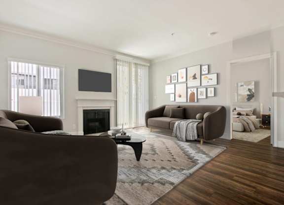 A living room with a brown couch, a fireplace, and a TV on the wall.