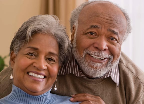 An older couple is smiling and embracing each other.